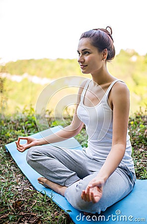 Pretty girl sitting in a meditation pose on the carpet Stock Photo