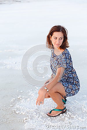 Pretty girl is squatting on the salt lake, expanse of Bascunchak salt lake Stock Photo