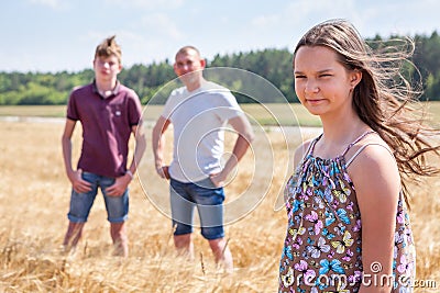 Pretty girl in summer light dress portrait with her father and brother on background, Caucasian family in wheat field Stock Photo
