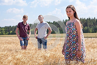 Pretty girl in summer light dress portrait with her father and preteen brother on background, Caucasian family in wheat fields Stock Photo