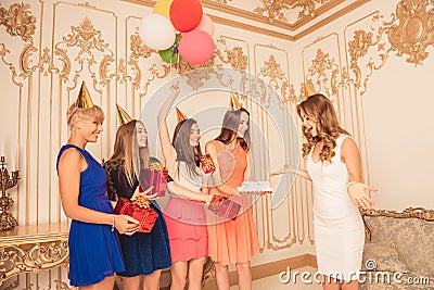 Pretty girls holding balloons and presents giving birthday cake Stock Photo