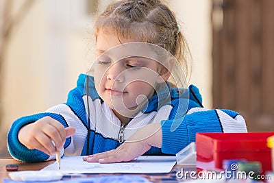 Pretty girls sitting at a table in courtyard of the house and draws pencil Stock Photo