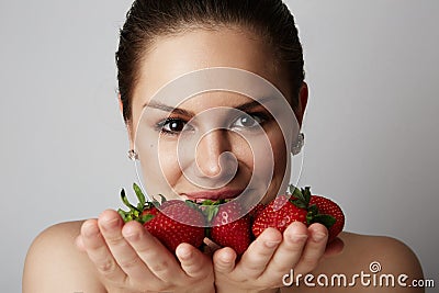 Pretty happy smiling girl with many strawberry over colorful white background.Portrait of brunette cutie with bowl of Stock Photo