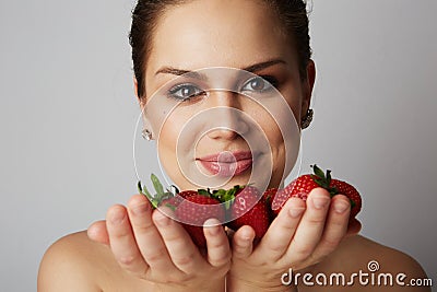 Pretty happy smiling girl with many strawberry over colorful white background.Portrait of brunette cutie with bowl of Stock Photo