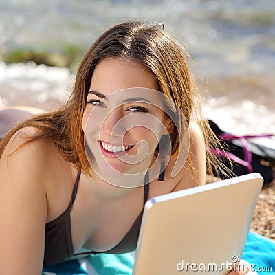 Pretty happy woman using a tablet on the beach Stock Photo