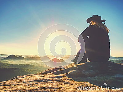 Pretty hiker backpacker sitting on peak edge and enjoying view Stock Photo