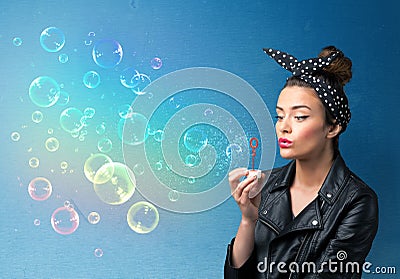 Pretty lady blowing colorful bubbles on blue background Stock Photo