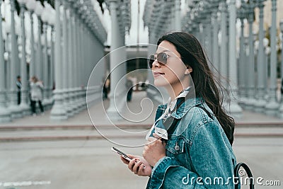 Lady holding her cellphone walking by the LACMA Stock Photo