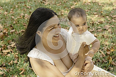 Pretty latin mother with baby in arms enjoying outdoors together Stock Photo