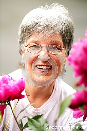 Pretty Laughing Older Lady by Her Flowers Stock Photo