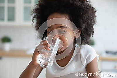 Pretty little African American girl drinking fresh water in kitchen Stock Photo