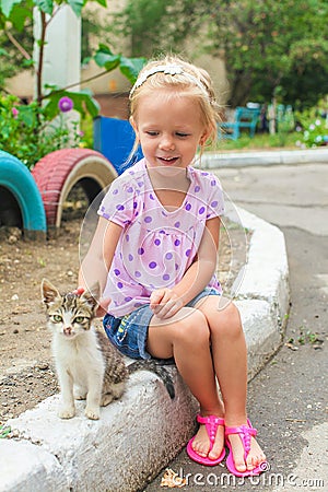 Pretty Little beautiful girl plays with a homeless Stock Photo