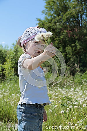 Pretty little gilr in hat holds dandelions and smiles Stock Photo