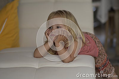 TV.Little girl watching TV lying on the couch. Stock Photo