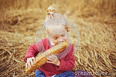 A pretty little girl eat a bread on a field Stock Photo