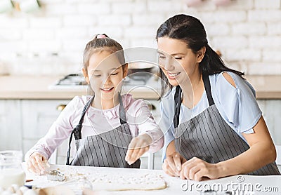 Pretty little girl and her attractive mom preparing pastry together Stock Photo