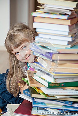 Pretty little girl hiding behind a stack of books Stock Photo