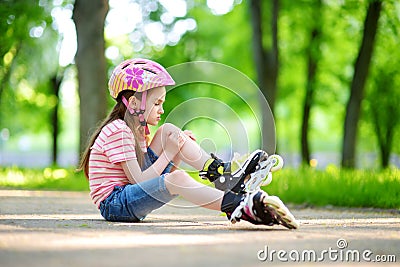 Pretty little girl learning to roller skate on beautiful summer day in a park Stock Photo