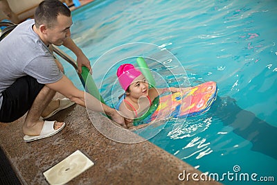 Pretty little girl learning to swim in the pool with swim coach trainer Stock Photo