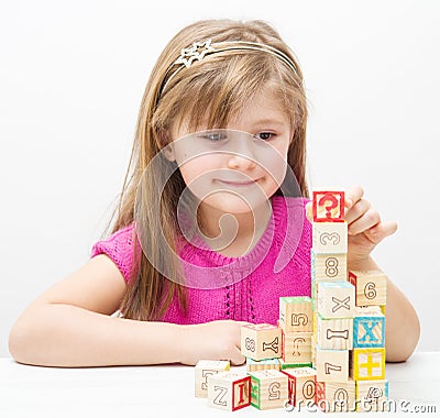 Pretty little girl playing with wooden cubes with letters and numbers Stock Photo