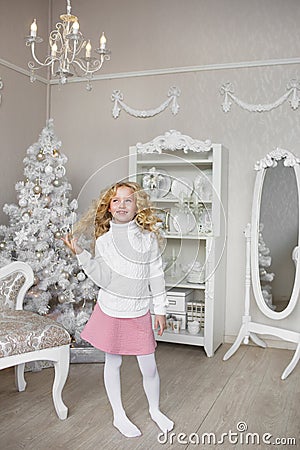 Pretty little girl stands and touches her hair in a light new year decoration studio Stock Photo