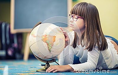 Pretty little student girl studying geography with globe in a child's room Stock Photo
