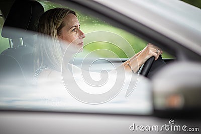 Pretty midle aged woman at the steering wheel of her car Stock Photo