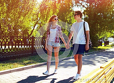 Pretty modern young couple in love walking in sunny summer day Stock Photo