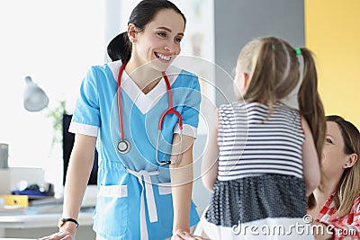 Pretty pediatrician chatting with cute patient child girl on appointment in clinic Stock Photo