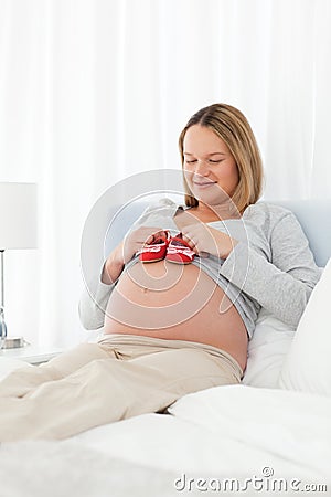 Pretty pregnant woman having baby shoes Stock Photo