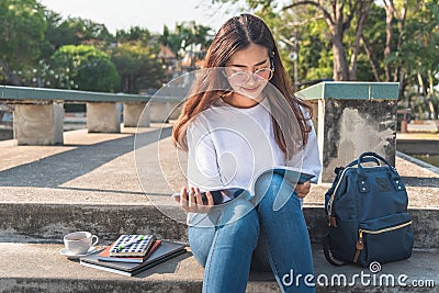 Pretty relaxed young woman reading a book at the lawn with sun shining Stock Photo