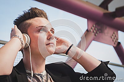 Pretty short hair girl listening to music on a bridge Stock Photo