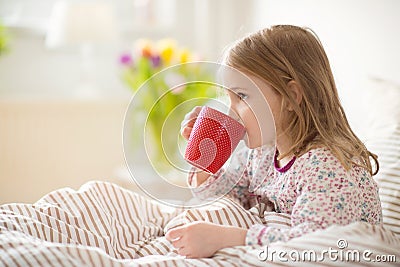 Pretty sick little child girl laying in bed drink tea Stock Photo