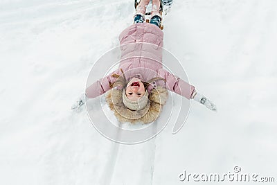 Pretty small girl enjoying winter outdoors. Little girl having fun with snow and sled in forest or park Stock Photo