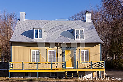 Pretty small yellow wooden ancestral neoclassical house with metal sheet roof in Saint-Jean Stock Photo