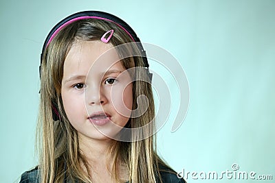 Pretty smiling cild girl listening to music in big pink earphones Stock Photo