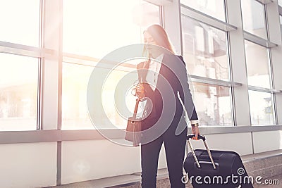 Pretty smiling female flight attendant carrying baggage going to airplane in the airport Stock Photo