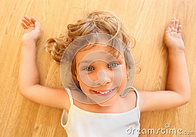 Pretty smiling little girl lies on floor Stock Photo