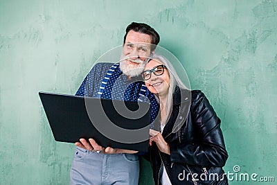 Pretty smiling senior woman in black leather jacket leaning her head on the shoulder of her handsome bearded man, while Stock Photo