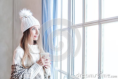 Pretty smiling winter woman holding hot dring and resting at home, romantic portrait Stock Photo