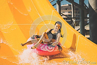 Smiling woman having fun on the water slide in aqua park Stock Photo