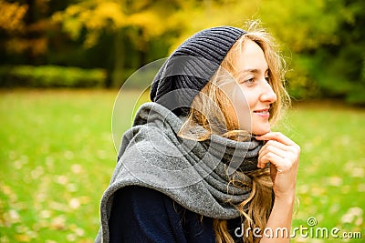 Pretty smiling woman wearing knitting hat and scarf thoughtfully looking side outdoor in the city park in fall season Stock Photo