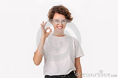 Pretty smiling woman in a white shirt and eyeglasses showing OK sign to express appreciation Stock Photo