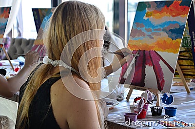 Pretty smiling young woman drawing a picture with paint. Front view on drawing girl with palette. Smiling young woman Stock Photo