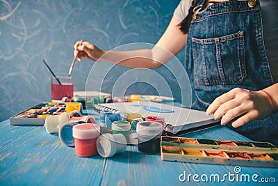 Pretty smiling young woman drawing a picture with poster paint Stock Photo