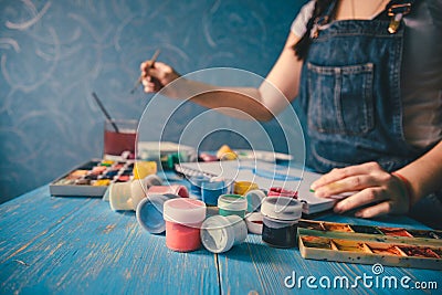 Pretty smiling young woman drawing a picture with poster paint Stock Photo