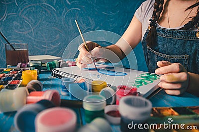 Pretty smiling young woman drawing a picture with poster paint Stock Photo