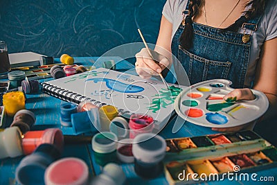 Pretty smiling young woman drawing a picture with poster paint Stock Photo