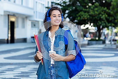 Pretty spanish female student with backpack and earphones Stock Photo