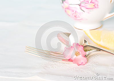 Tea Cup, Fork and Spoon with sugar cube and lemon on white table cloth Stock Photo